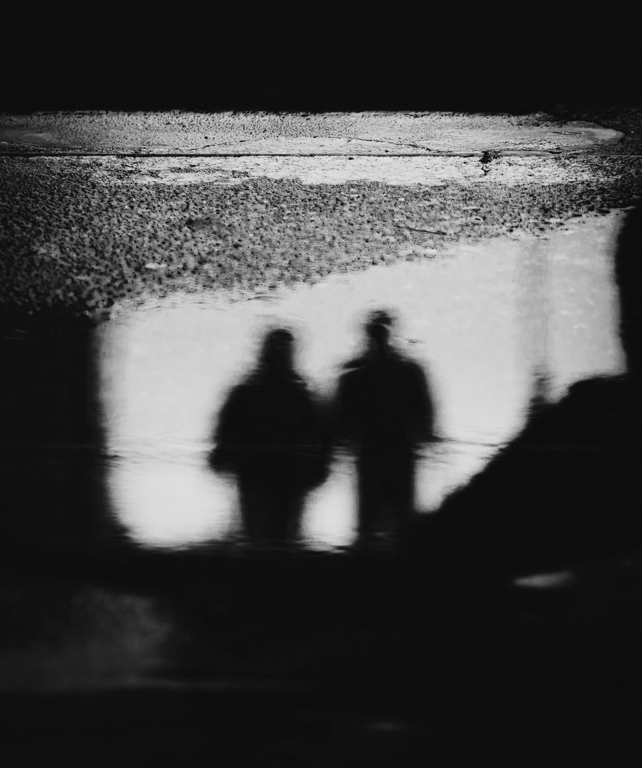 Black and white abstract reflection of two figures in a puddle in Baguio, Philippines.
